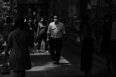 Rear view of people walking on street in city