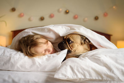 Girl with dog lying down on bed at home