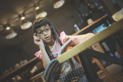 Girl reading book at table in restaurant