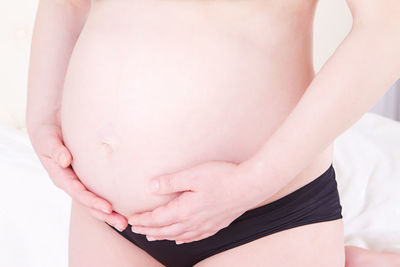 Midsection of pregnant woman with hands on stomach