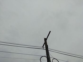 Low angle view of bird on cable against sky