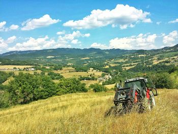 Scenic view of agricultural field against sky and tractor working near assisi, umbria, italy