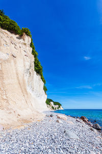Rock formation on beach against blue sky