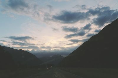 Road amidst mountains against sky during sunset