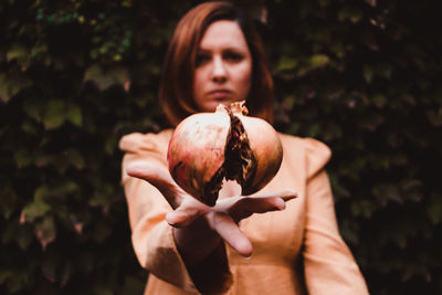 Portrait of woman holding apple against blurred background