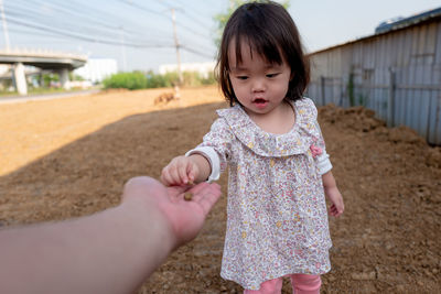 Baby girl giving stone to person on field