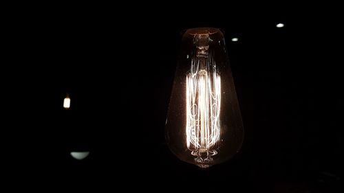 Close-up of illuminated light bulb against black background