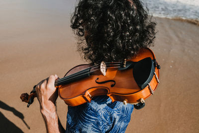 Midsection of woman playing guitar at beach