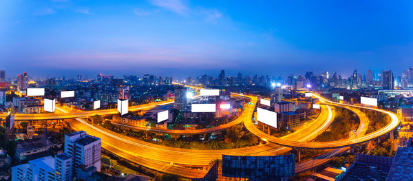 High angle view of illuminated city by buildings at dusk