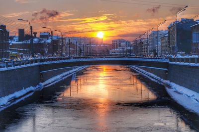 Bridge over river in city during sunset