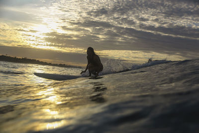 Young woman surfing at sunrise