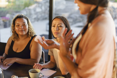 Woman explaining crystal to female friends at retreat center