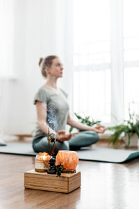 Beautiful happy girl with closed eyes practicing yoga in lotus position in bedroom in the morning