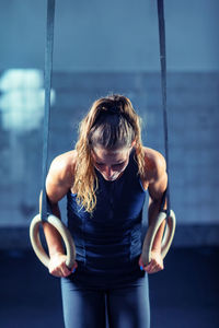 Female athlete exercising with gymnastic rings in gym