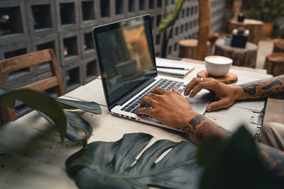 Midsection of man using mobile phone while sitting on table