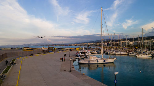 Sailboats moored at harbor against sky