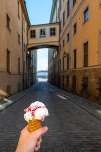 Hand holding ice cream cone on street