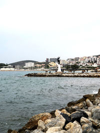 Sea by buildings against clear sky