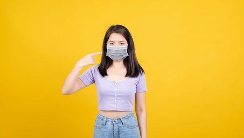 Portrait of smiling woman against yellow background