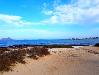 Scenic view of beach against blue sky