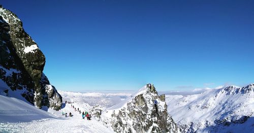 Panoramic view of snowcapped mountains against clear blue sky