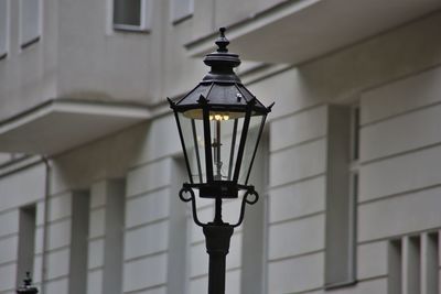 Low angle view of illuminated street light against building