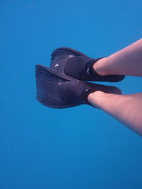 Low section of person wearing diving flipper while swimming in sea