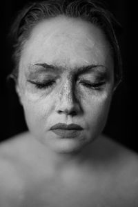 Close-up of woman wearing facial mask against black background