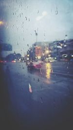 Cars on road seen through wet window in rainy season