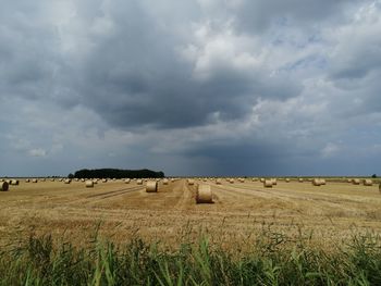 Hay bales on field against sky