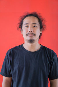 Portrait of young man standing against yellow wall