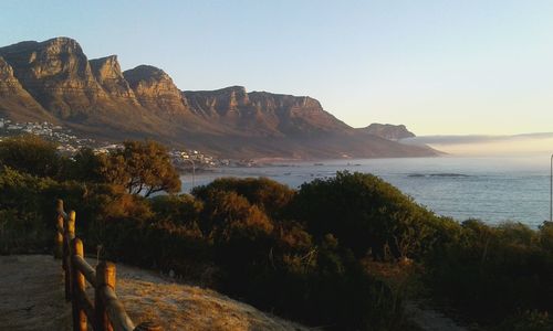 Scenic view of sea by mountains against clear sky