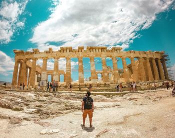 Full length of man standing at old ruin against sky on sunny day