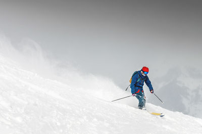 Skiing, skier, frisky - freeride, a man is stylishly skiing on a snowy slope with snow dust plume