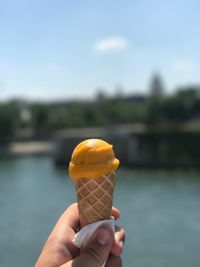 Close-up of hand holding ice cream against lake