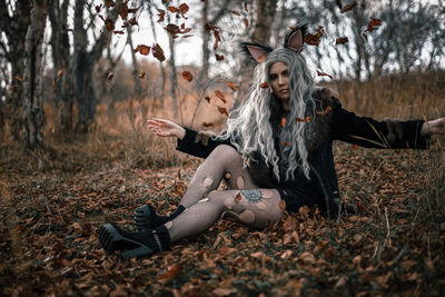 Young woman with leaves on field in forest