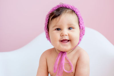 Portrait of cute smiling boy against pink background