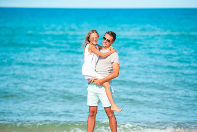 Full length of smiling young woman standing on beach