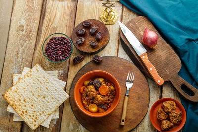 Jewish dish chelnt with meat in a plate on a wooden table on a stand next to ingredients. horizontal