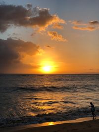 Silhouette man standing on beach against sky during sunset