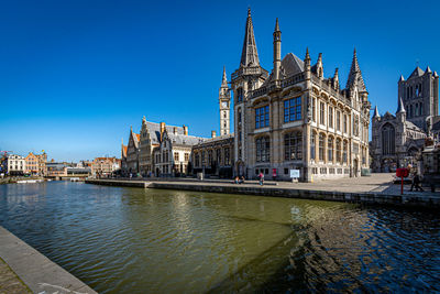 Buildings by river against blue sky in locked down city