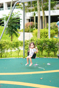 Blurry photo of an active little toddler child playing swing at the playground. happy and fun time.