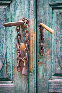 Close-up of old wooden door with rusty padlock and chain