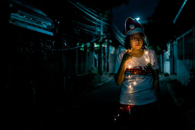 Rear view of woman standing against illuminated night