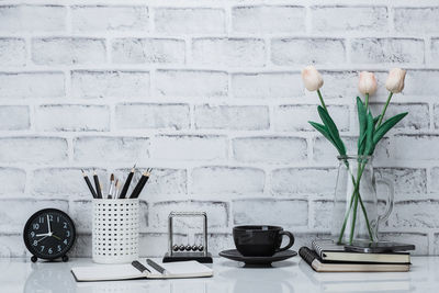 Flower vase on table against wall