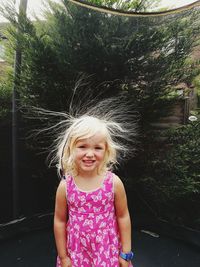 Portrait of smiling girl standing against trees