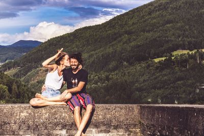 Full length of smiling young woman against mountains