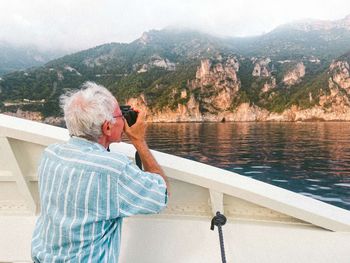 Picture of an old man taking a picture of the beautiful amalfi coast.