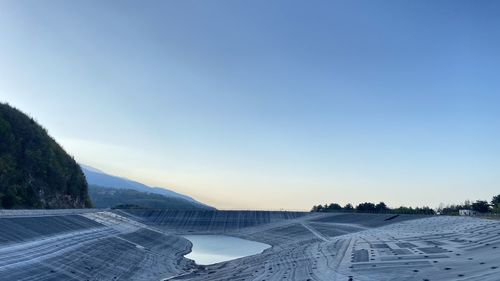 Scenic view of lake and landscape against clear blue sky