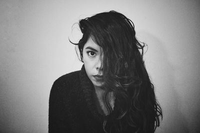 Portrait of young woman with messy hair against wall